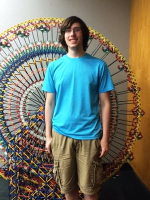 Rodon Intern Steven Yost Stands in front of a ferris wheel made of k'nex